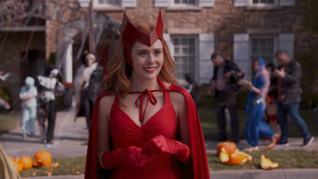 Scarlet Witch standing in a red outfit smiling in a festive neighborhood scene