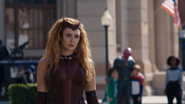 Scarlet Witch in detailed red costume standing outdoors with blurred people in background
