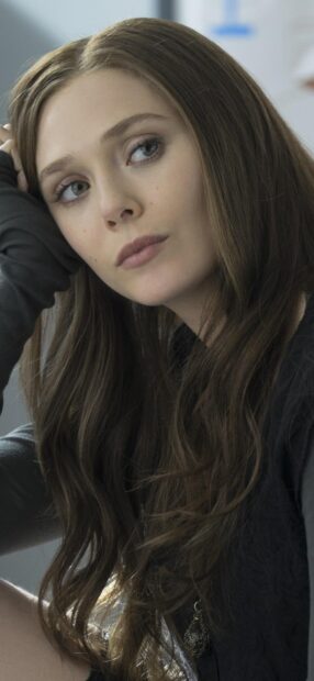 Scarlet Witch in a thoughtful pose with long brown hair and blue eyes
