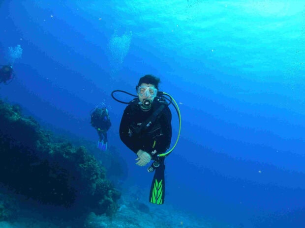 Scuba diving gear with diver exploring underwater reef in clear blue ocean
