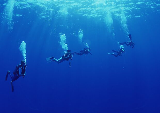 A group of scuba divers exploring deep blue ocean waters in clear visibility