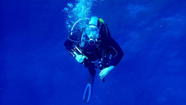 Scuba diving activity captured underwater with a diver in full gear surrounded by deep blue water