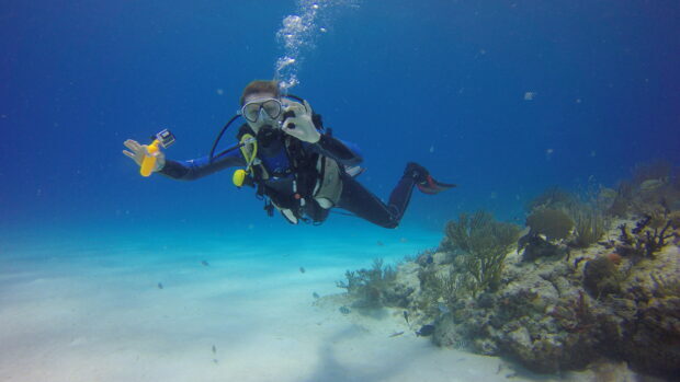 Scuba diving enthusiast exploring coral reef underwater in clear blue ocean