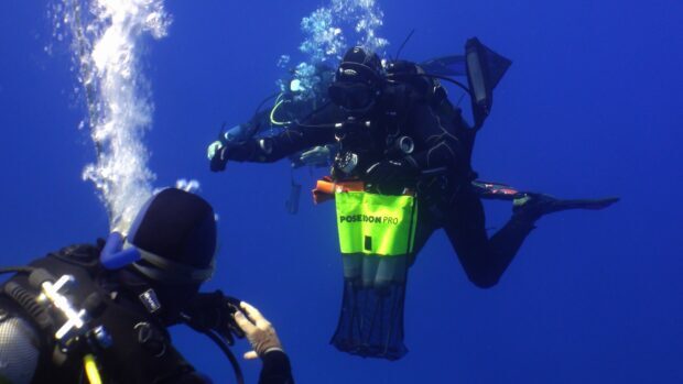 Two scuba divers exploring underwater with diving equipment and neon yellow Poseidon Pro gear
