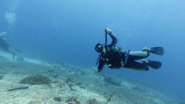 Scuba diver exploring underwater coral reef in clear blue water