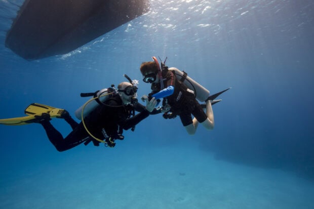 Two experienced divers communicating underwater during scuba diving session