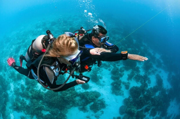 Two scuba divers exploring underwater with scuba gear in clear blue ocean