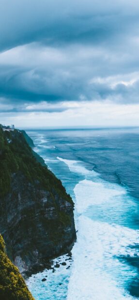 Cliffside seascape with waves crashing and cloudy sky