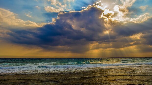 Dark clouds over the seascape with golden sunlight shining through the sky