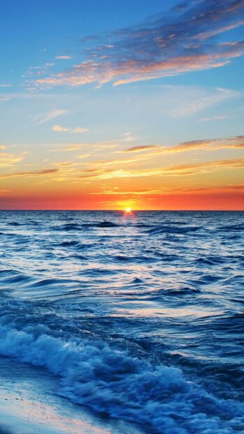 Calm seascape at sunset with waves gently rolling onto the shore