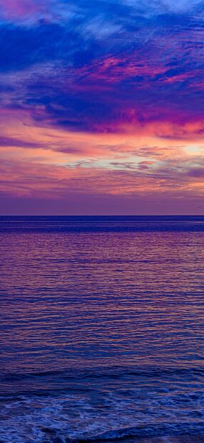 Calm ocean waves under a colorful seascape sky at sunset
