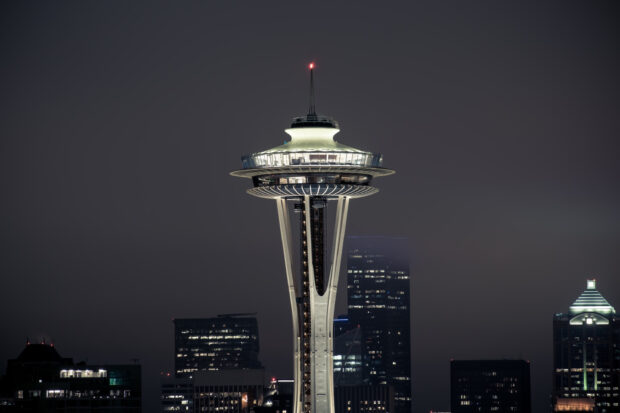 The Seattle iconic Space Needle illuminated at night with city buildings in the background