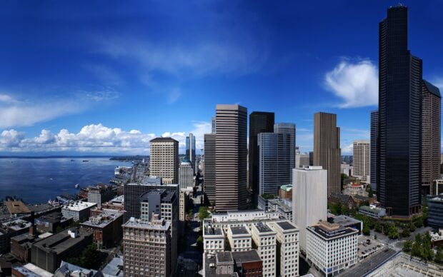 A clear blue sky above downtown Seattle skyline with tall office buildings and waterfront views