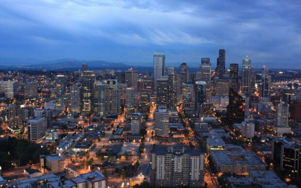 Evening cityscape of Seattle with illuminated buildings and streets under a cloudy sky