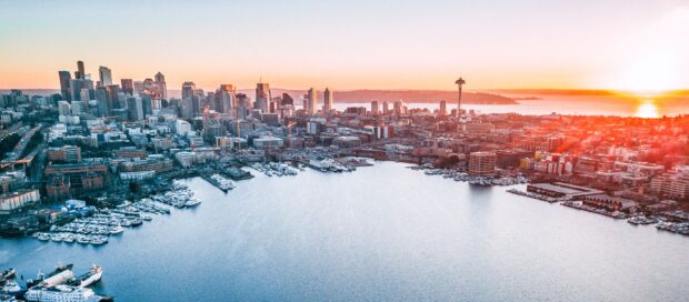 Aerial view of Seattle city skyline at sunset with boats in the harbor and water in the foreground