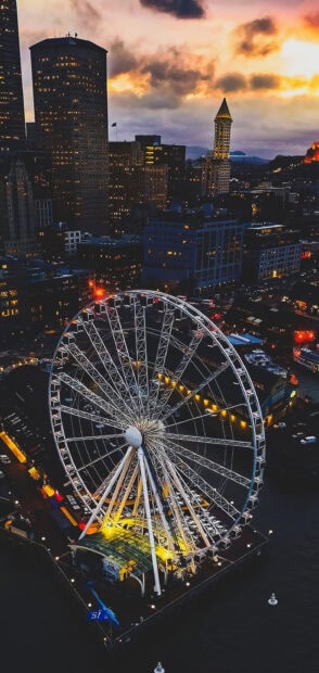 Seattle Ferris wheel illuminated at dusk with city skyline in the background
