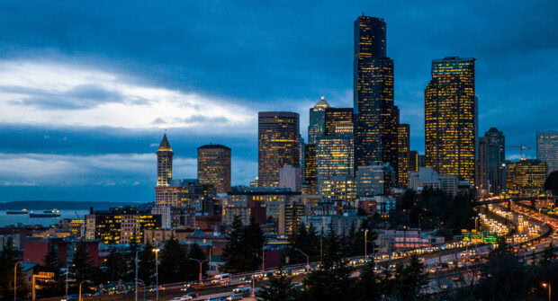 Seattle city skyline at dusk with illuminated buildings and busy highway traffic