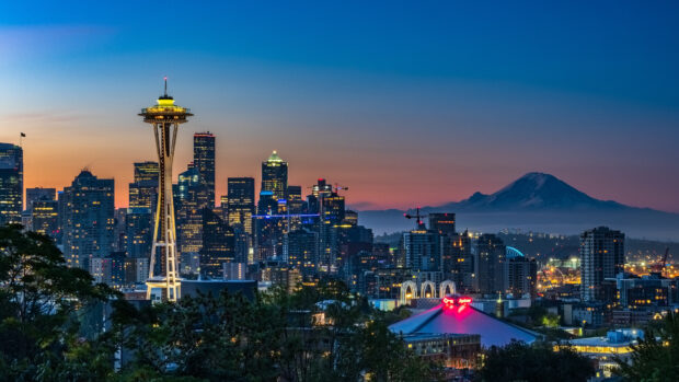 Seattle city skyline with the iconic Space Needle and Mount Rainier in the background at dusk