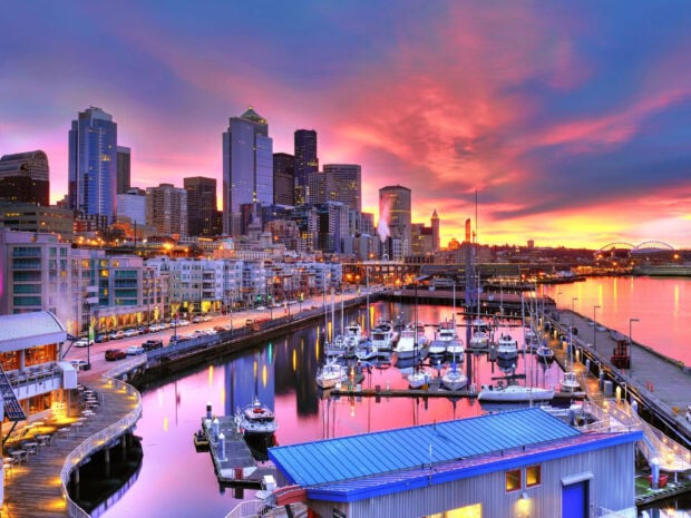 Colorful Seattle skyline at sunset with cityscape and marina boats reflecting on water