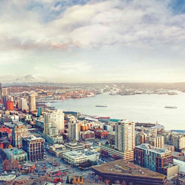 A panoramic view of Seattle city with Mount Rainier in the distance and urban buildings along the waterfront