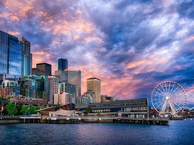 Seattle skyline with aquarium and ferris wheel under colorful sky at sunset