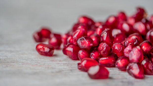 Close up of red seeds on a wooden surface showing detailed texture and color