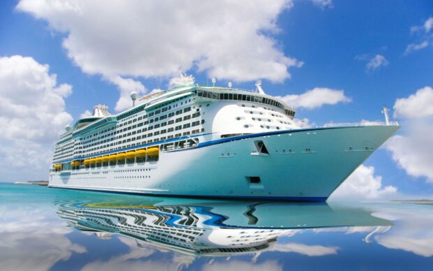 Large cruise ship sailing on calm sea with clear sky and reflection in water