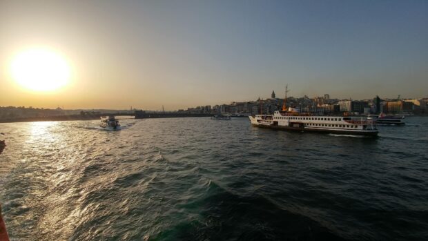 Ship cruising on the water near the city during sunset with clear sky