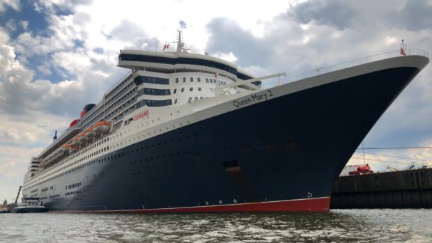 The large ship Queen Mary 2 docked at the harbor under cloudy sky