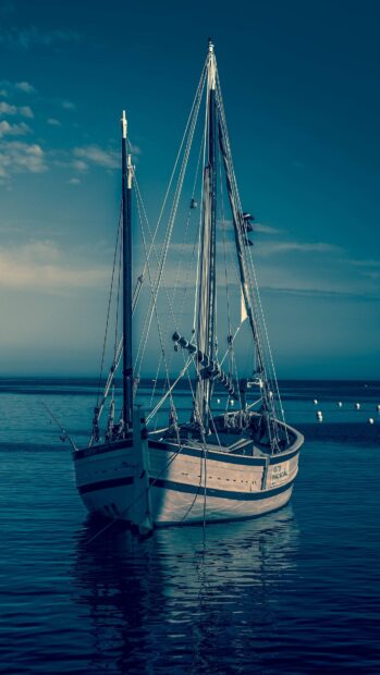 A classic ship floating calmly on the ocean under a clear blue sky