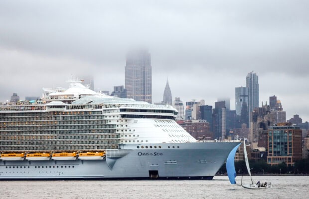 A large cruise ship sailing near the city skyline under cloudy sky