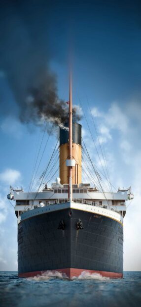 Front view of a large ship emitting black smoke while sailing on the ocean