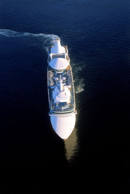 White ship cruising through deep blue ocean water with wake behind ship