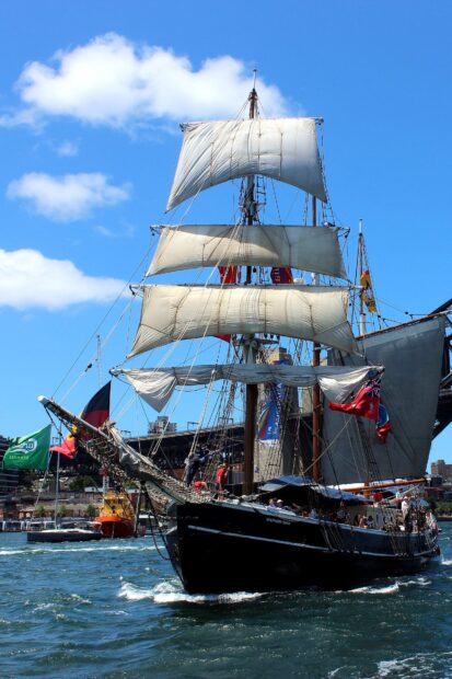 A large sailing ship with white sails on the water during a sunny day