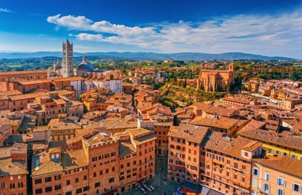 The historic Siena cityscape featuring ancient buildings and a cathedral under a blue sky
