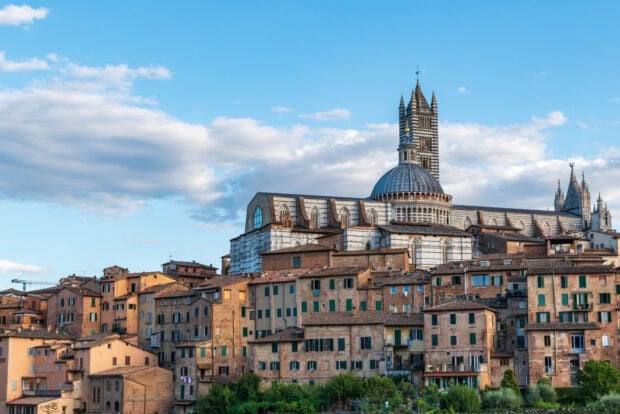 Historic Siena cityscape with cathedral under blue sky in Italy