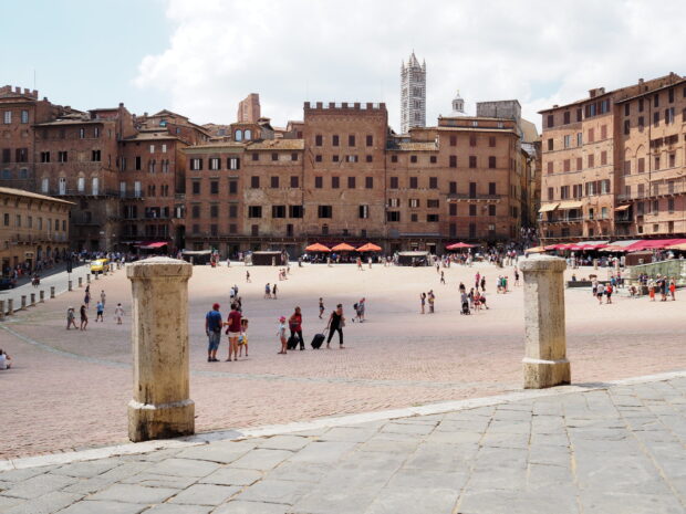 Siena historic square with old brick buildings and tourists in summer