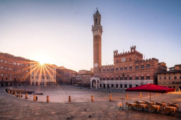 The Siena square with historic buildings and morning sunlight rays