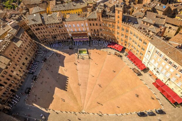 Aerial view of Siena historic square with red umbrellas and old buildings