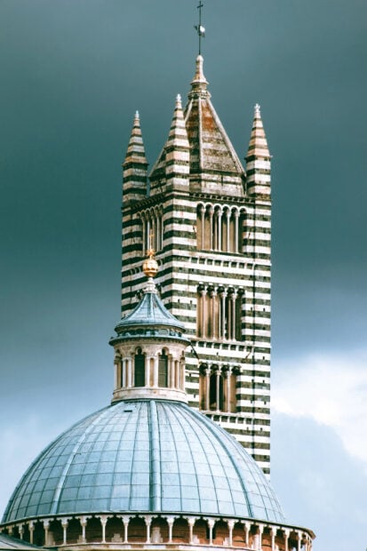 Historic Siena architecture with striped tower and dome under cloudy sky