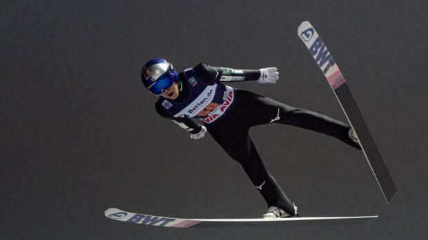 A ski jumper in mid air performing a jump at a competition with race number 56