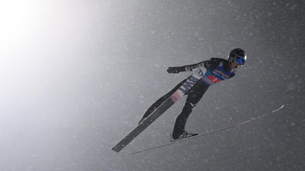 A ski jumper soaring through snowy air during a winter competition