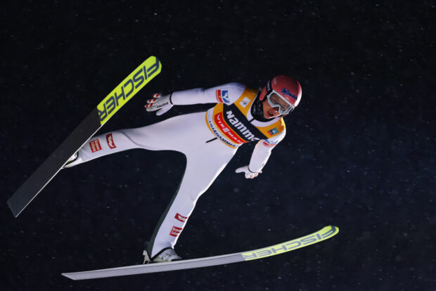Male ski jumper in flight during a competition in midair