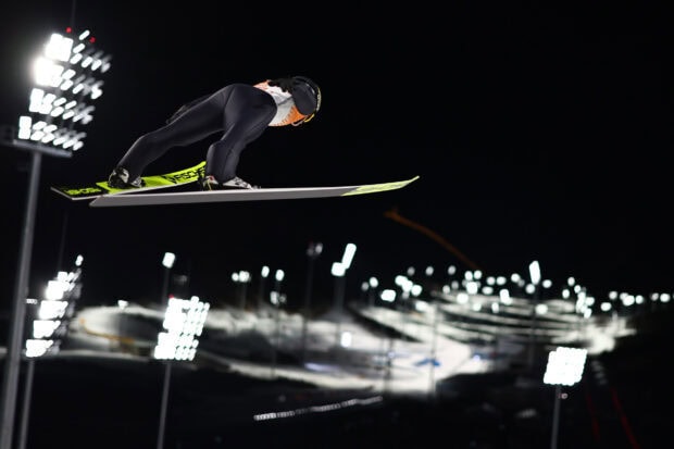 Male ski jumper in midair during a night ski jumping competition