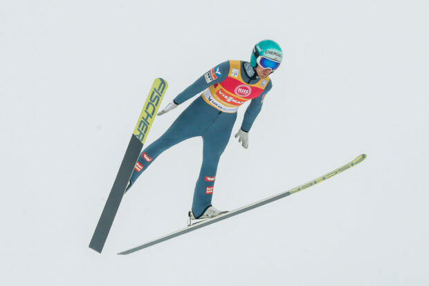 Ski jumping athlete in full flight during a competition wearing helmet and goggles