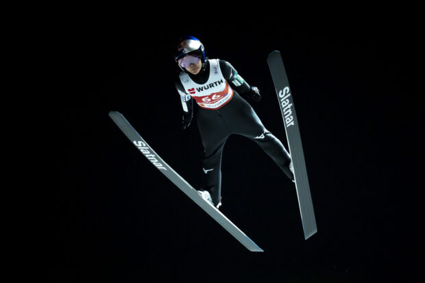 Ski jumping athlete in mid air performing a ski jumping technique