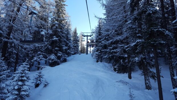 Ski lift running through snowy forest with snow covered trees on both sides
