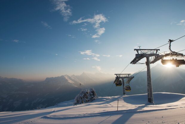 Ski lift on snowy mountain with clear sky and mountain range in the background