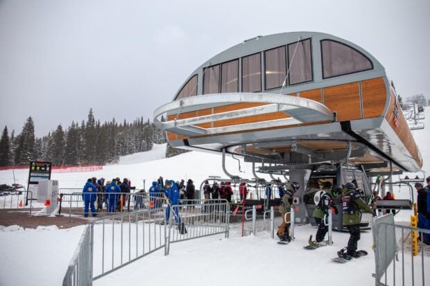 Ski lift station with skiers and snowboarders waiting in line at a snowy mountain resort