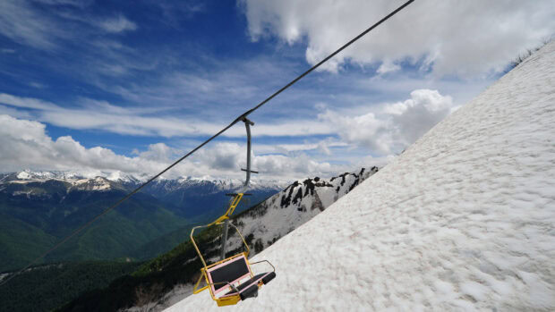 A ski lift ascending snowy mountains with a clear sky over the alpine landscape